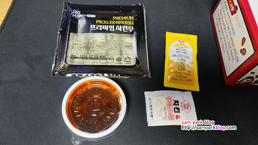 치킨무, 양념치킨 소스, 허니머스타드 드레싱, 양념소금이 나열되어 있는 구성품 사진